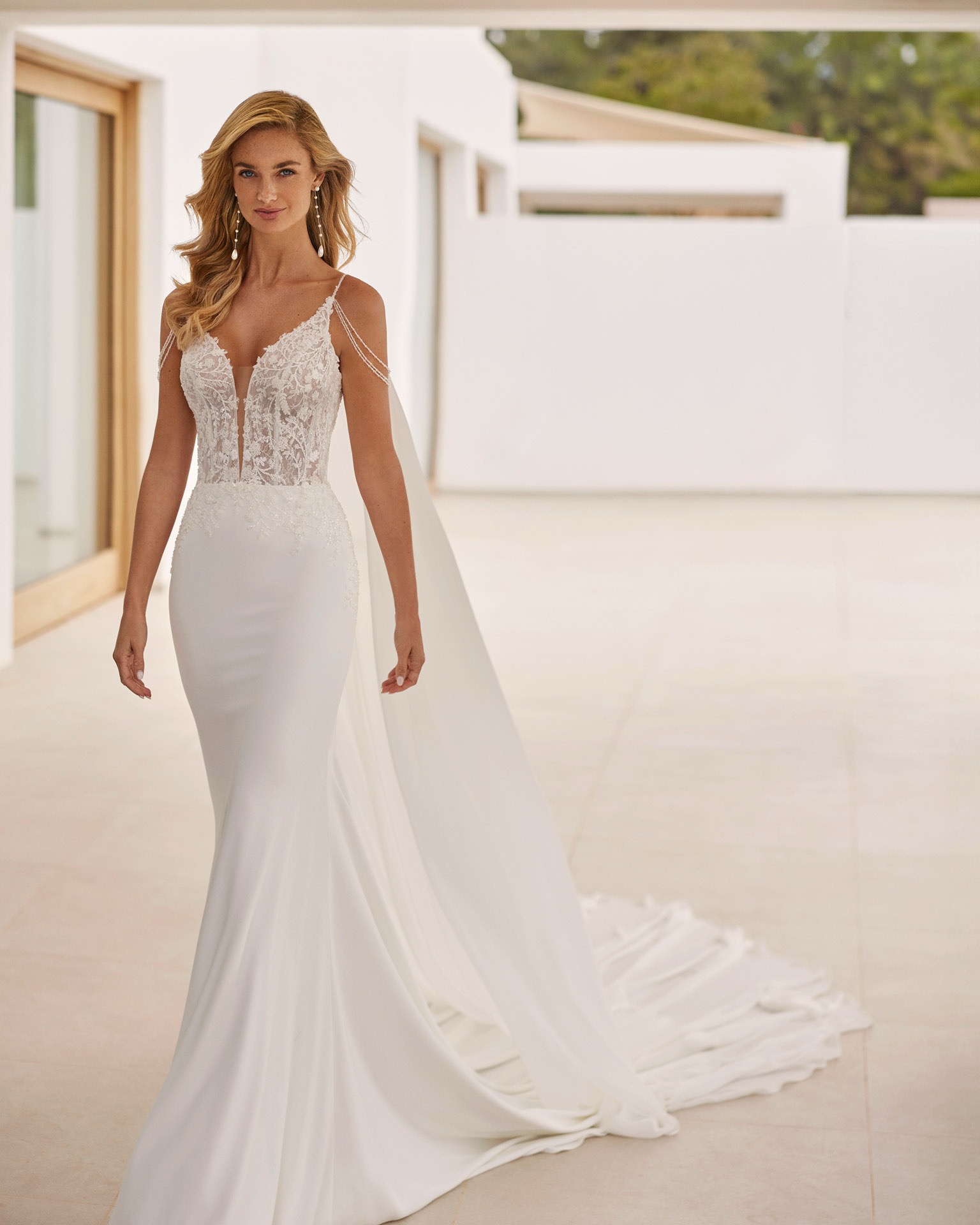 Sadoc van Adriana Alier Rosa Clara, zeemeermintrouwjurk met kanten bovenstuk en afhangende parelbandjes.